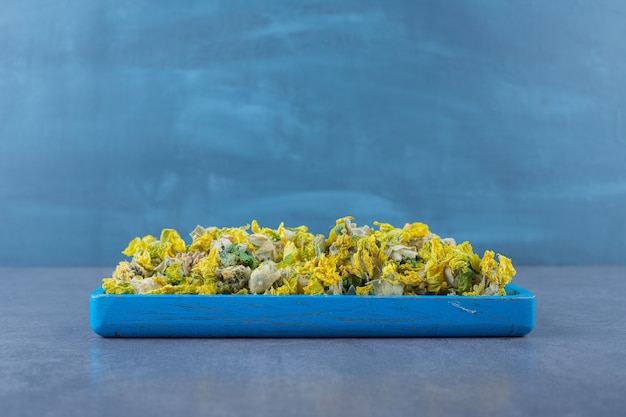 Free photo dried flowers on blue wooden tray over grey.