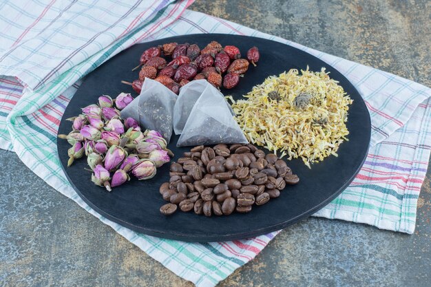 Dried flowers, coffee beans, rosehips and teabags on black board.