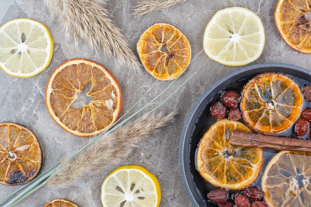 Dried and fresh lemon slices with cinnamon on stone surface. 