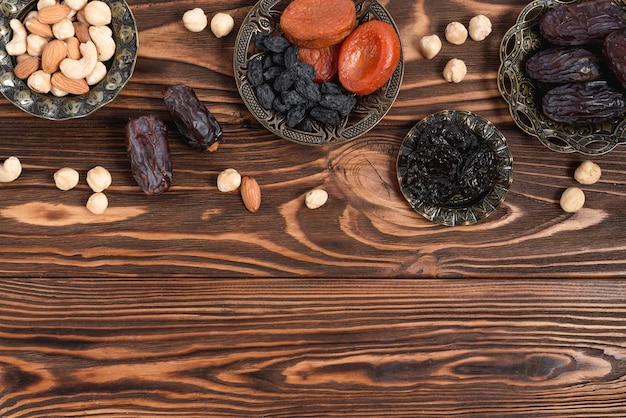 Dried fruits; nuts and fresh dates on wooden texture table