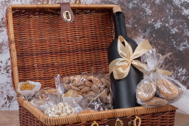 Dried fruits and nuts packed in plastic bags with wooden bag with bottle of wine.