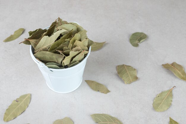 Dried green bay leaves in a ceramic cup.