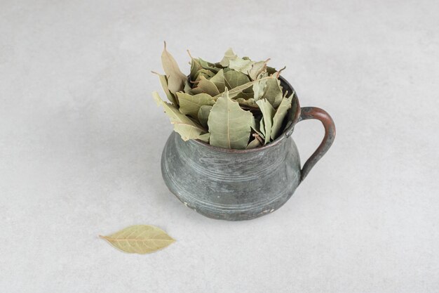 Dried green bay leaves in a metallic pot.