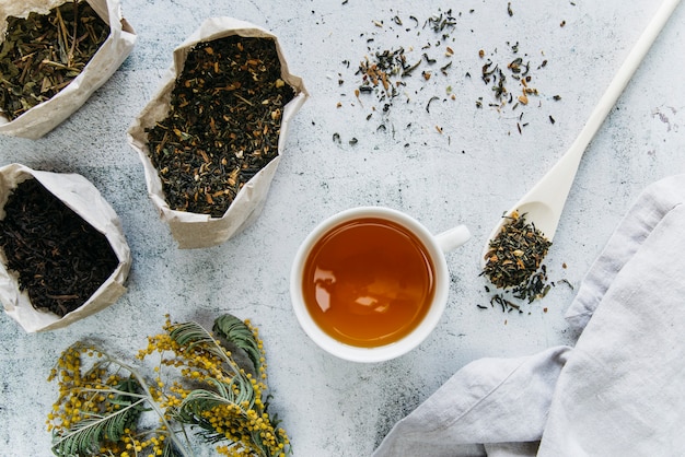 Dried herbal tea with tea cup on concrete backdrop