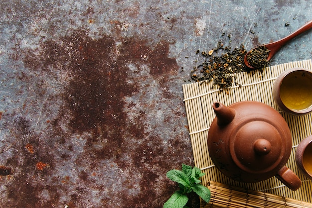 Dried herbs; mint; teapot and herbal tea on placemat over the rustic backdrop