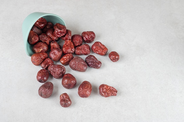 Dried Indian jujube berries in a cup on concrete.