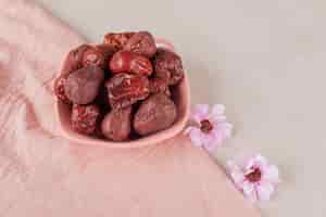 Free photo dried jujube berries in a cup on concrete.