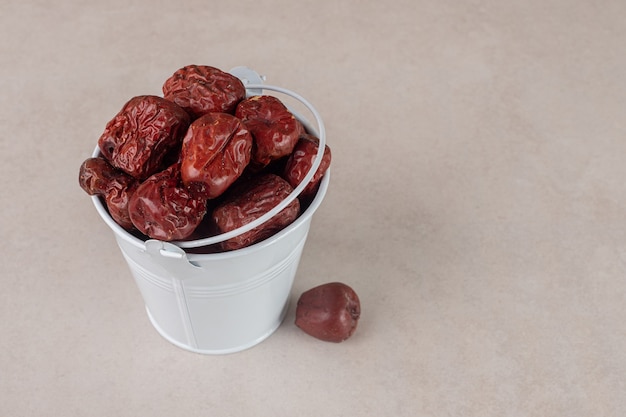 Free photo dried jujube berries in a cup on concrete.