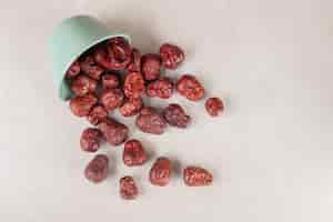 Free photo dried jujube berries in a cup on concrete.