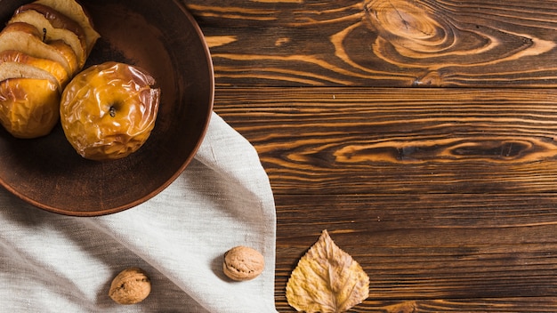 Free Photo dried leaf and nut near baked apple and cloth