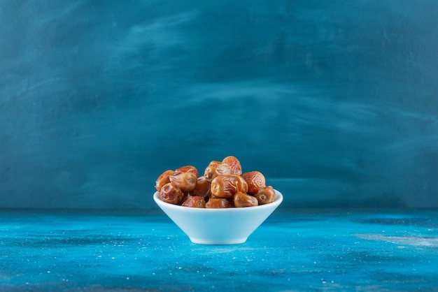 Free photo dried oleaster in a bowl on the blue surface