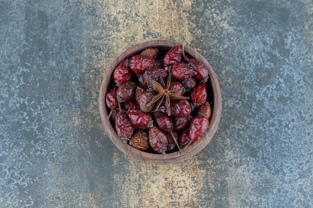 Dried organic rose hips in wooden bowl.