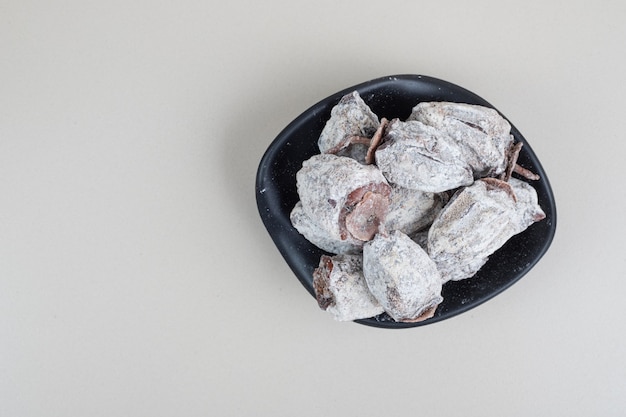 Dried persimmon fruits in black bowl