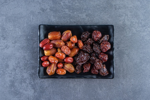 Free Photo dried plum and oleaster on a plate, on the marble surface