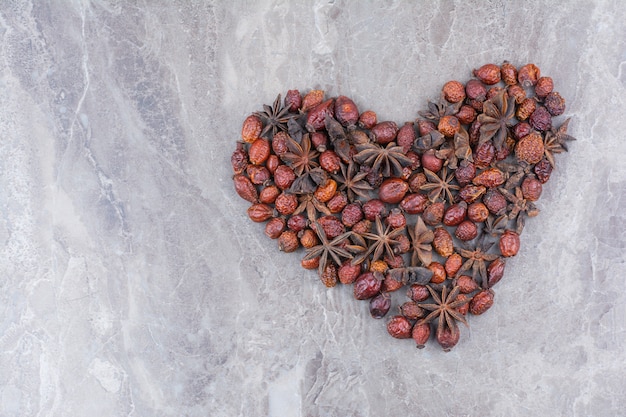 Dried rosehips with star anise on marble background.