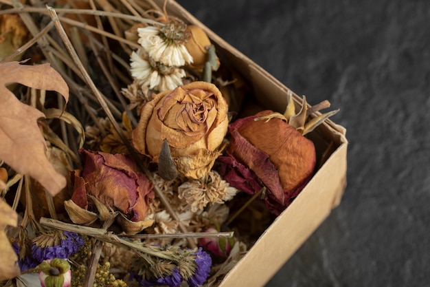 Dried roses flowers with dried leaves in a paper box . 