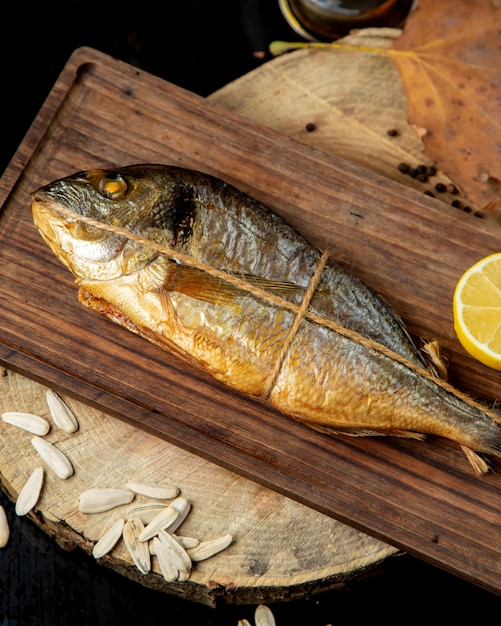 Dried smoked fish wrapped in rope served with lemon half on wooden board