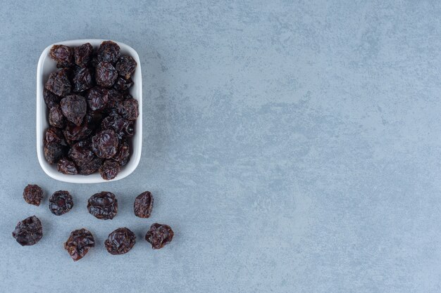 Dried sour cherries in the bowl, on the marble table. 