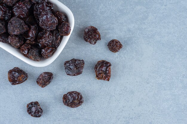 Dried sour cherries in the bowl, on the marble table. 