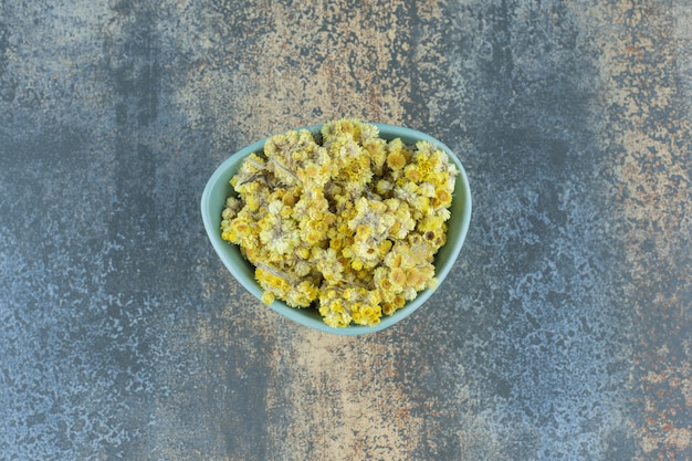 Dried yellow flowers in blue bowl.