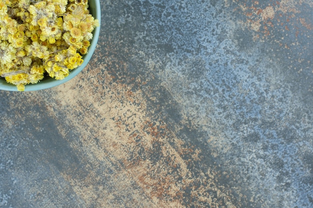 Dried yellow flowers in blue bowl.