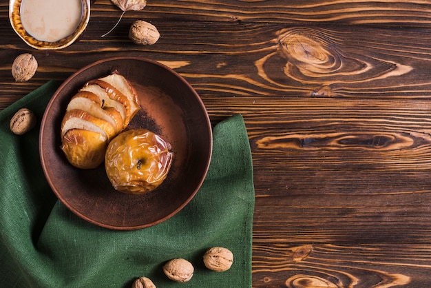 Drink and nuts near baked apples and napkin