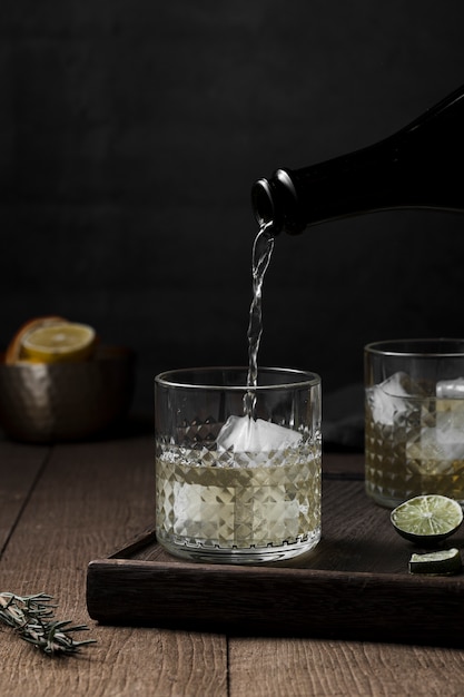 Drink pouring in glass with ice cubes