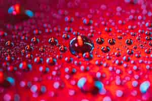 Free photo drop of water bubbles on the surface of red background