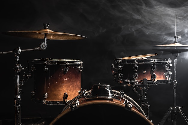 Drum kit on a dark background with stage lighting, copy space.