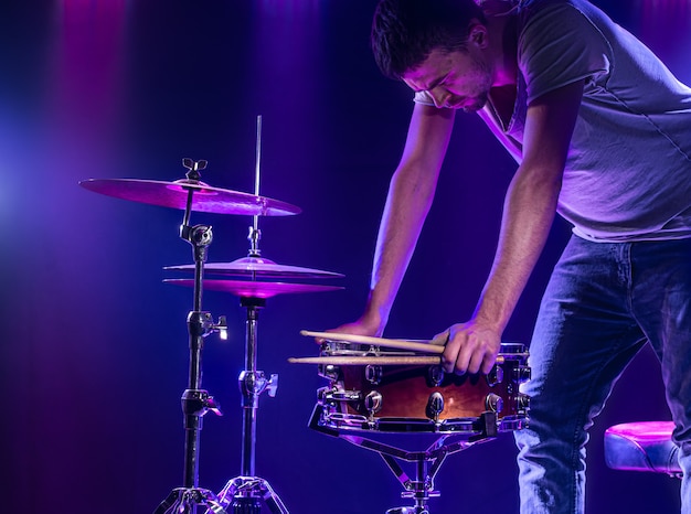 A drummer plays drums on a blue wall