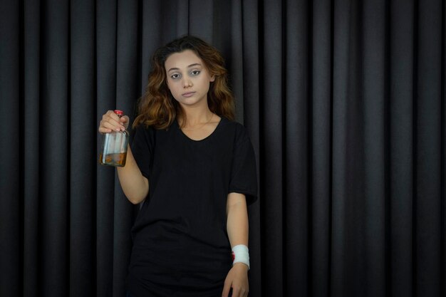 Drunk girl holding alcohol bottle and looking at the camera. High quality photo