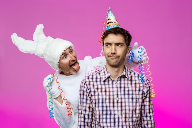 Free photo drunk man and rabbit at birthday party over purple wall.