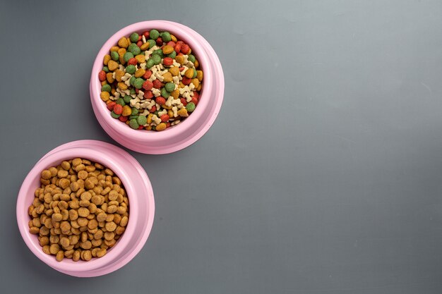 Dry dog food in bowl on dark wooden surface