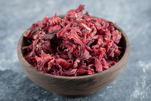 Dry hibiscus petals in wooden bowl.