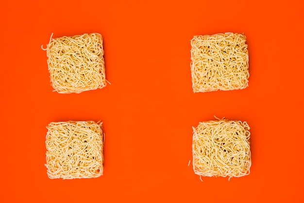 Free Photo dry instant noodles arranged on plain bright orange surface