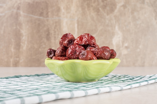 Dry jujube berries in a cup on concrete.