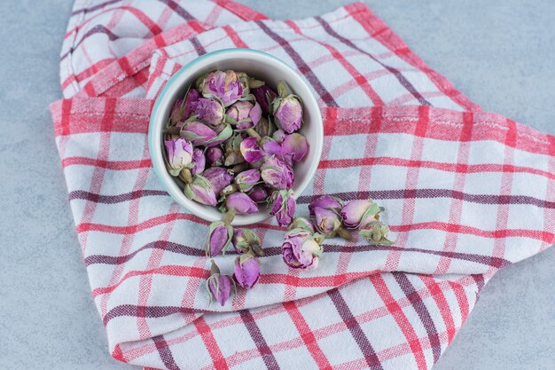 Dry rose flower in the bowl on towel on marble.