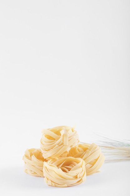 Free photo dry tagliatelle nests on white.