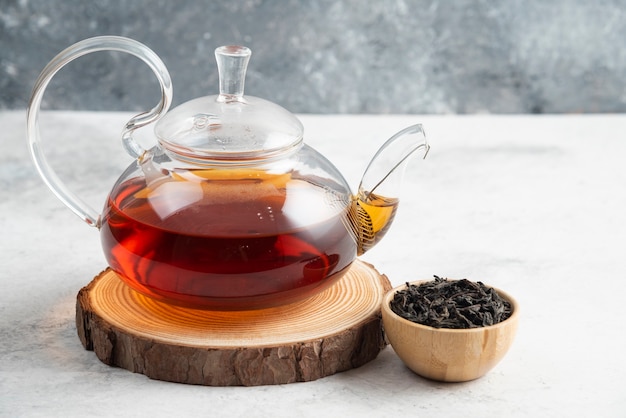 Free photo dry tea leaves with teapot on wooden board.