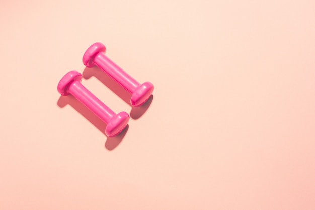 Dumbbells flat lay on pink background