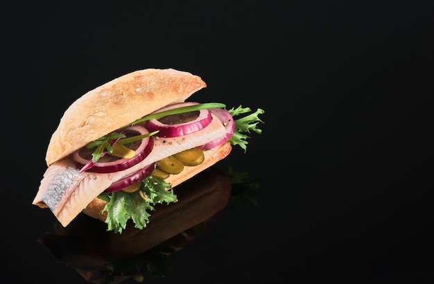 Free photo dutch sandwich with herring and pickles pickled cucumber and red onion on the dark mirror table. close up, selective focus and copy space