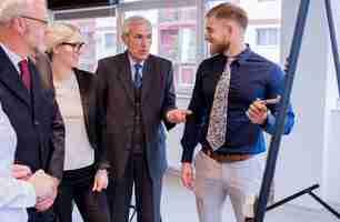 Free photo dynamic business team discussing around a flip chart white board in meeting room