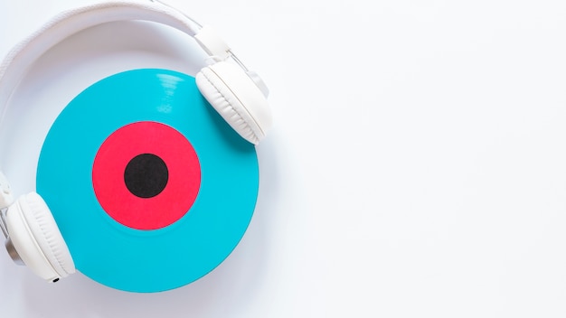 Earphones and vinyl disc on plain background