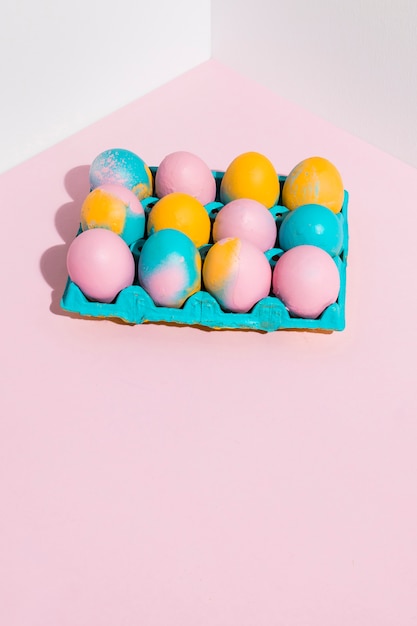 Free photo easter eggs in blue rack on pink table