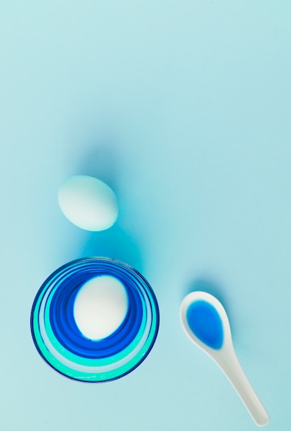 Easter eggs near bowl and spoon with dye liquid