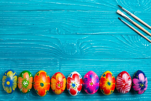 Easter eggs and paint brushes on wooden surface