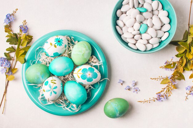 Easter eggs on plate near little stones in bowl and flower twigs