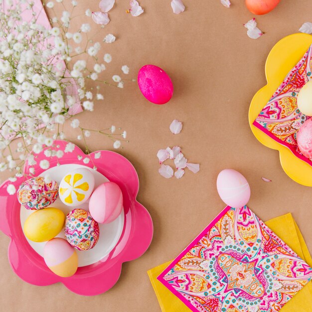 Easter eggs on plate near napkins and flowers