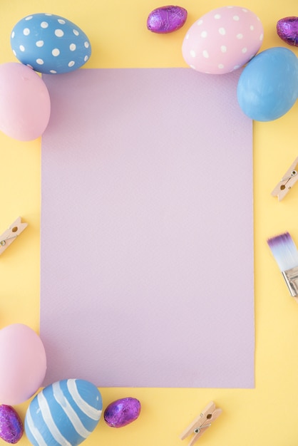 Easter eggs with blank paper on yellow table