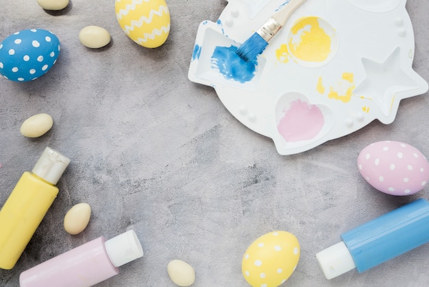 Easter eggs with glue sticks and paint palette on table